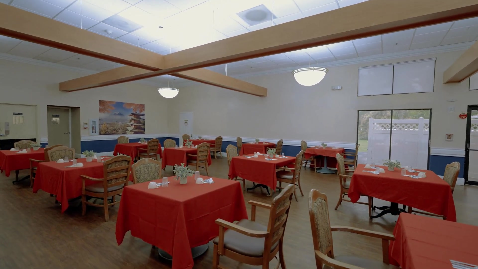 Restaurant-style senior dining room at Colonial Gardens assisted living in Lauderhill FL with red tablecloths and home-style meal service