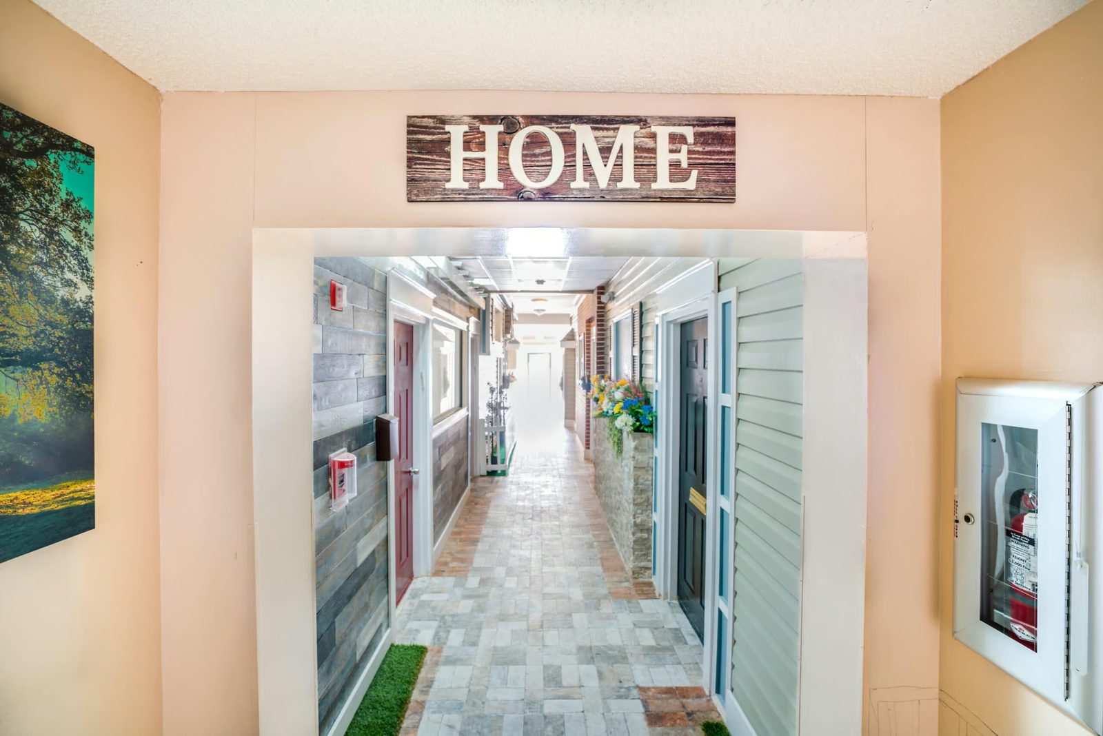 'HOME' sign over the entrance to a neighborhood-style hallway at Colonial Gardens assisted living in Lauderhill, FL